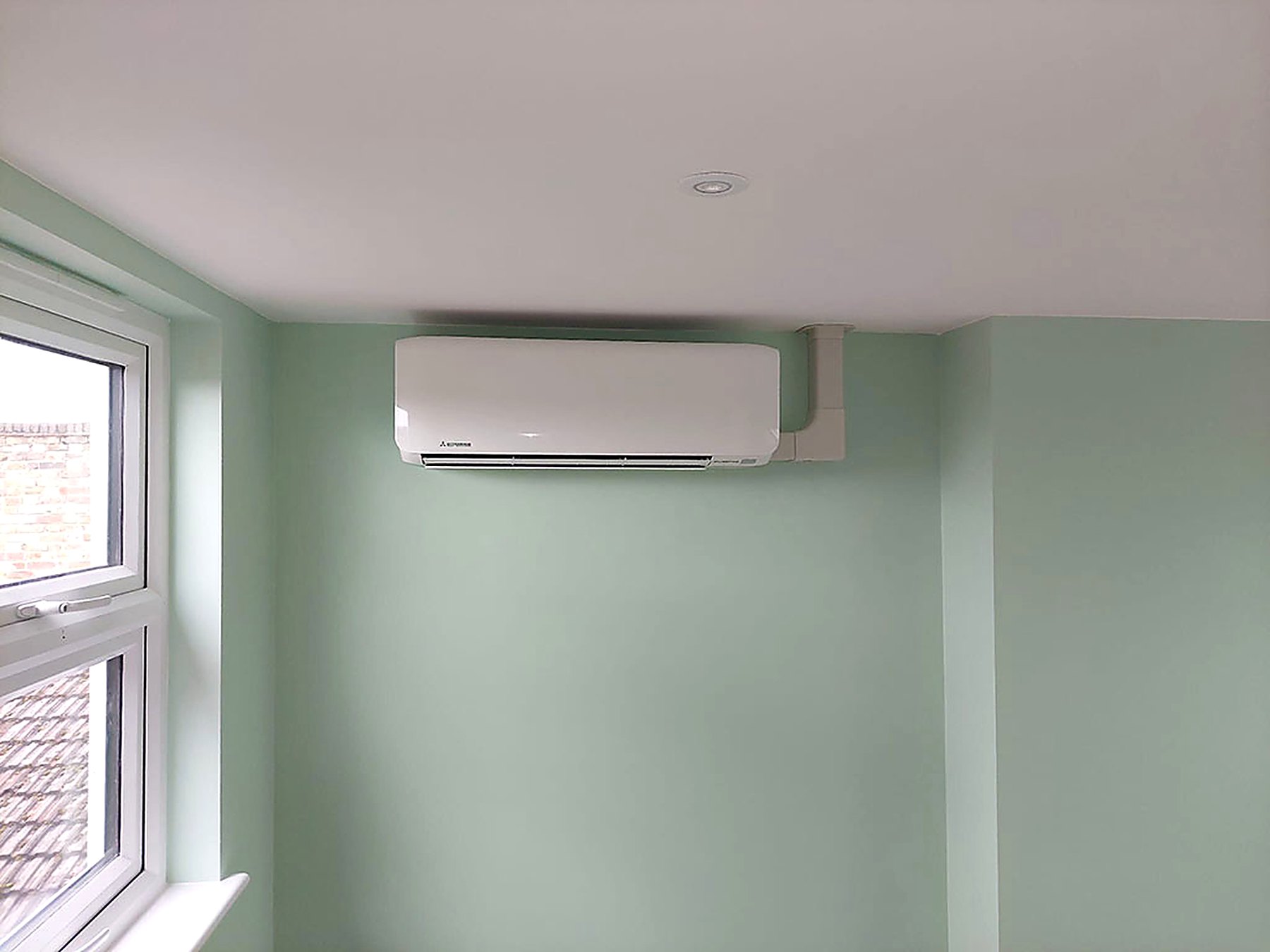 Discreet unit fitted high on the wall of a green painted room